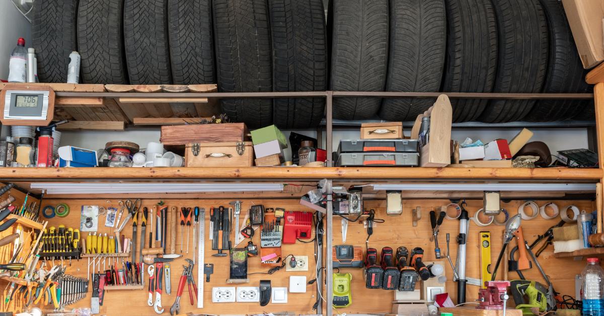 A garage shelving area with tires stored on the top shelf and heavy-duty shelving underneath for tools.