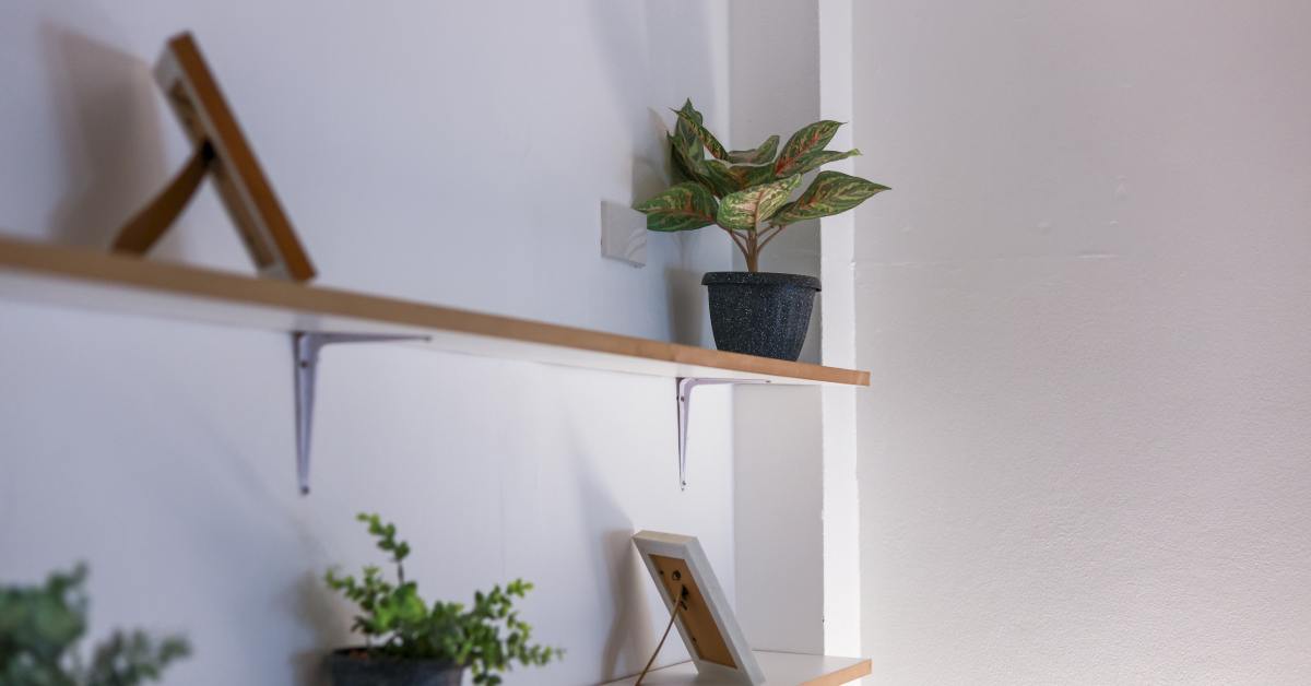 Two plain pine board floating shelves with standard steel shelf brackets holding them up on the wall.